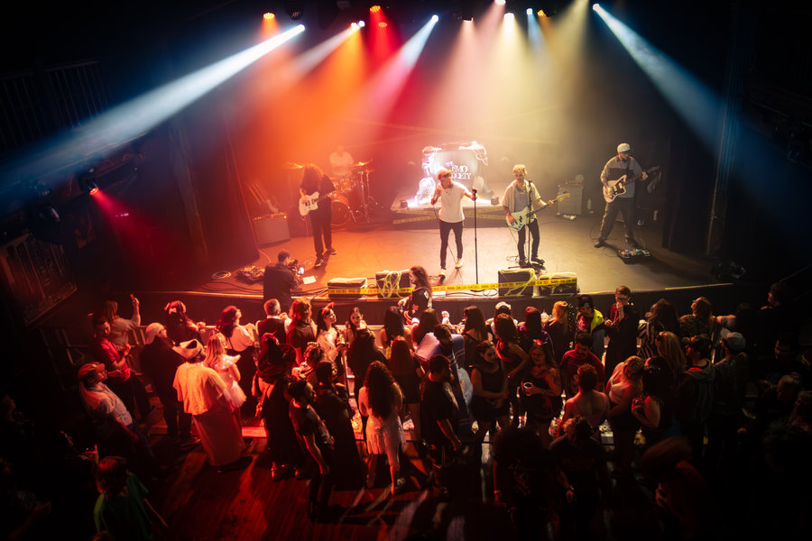 Singer silhouetted against warm stage lights in a haze-filled venue